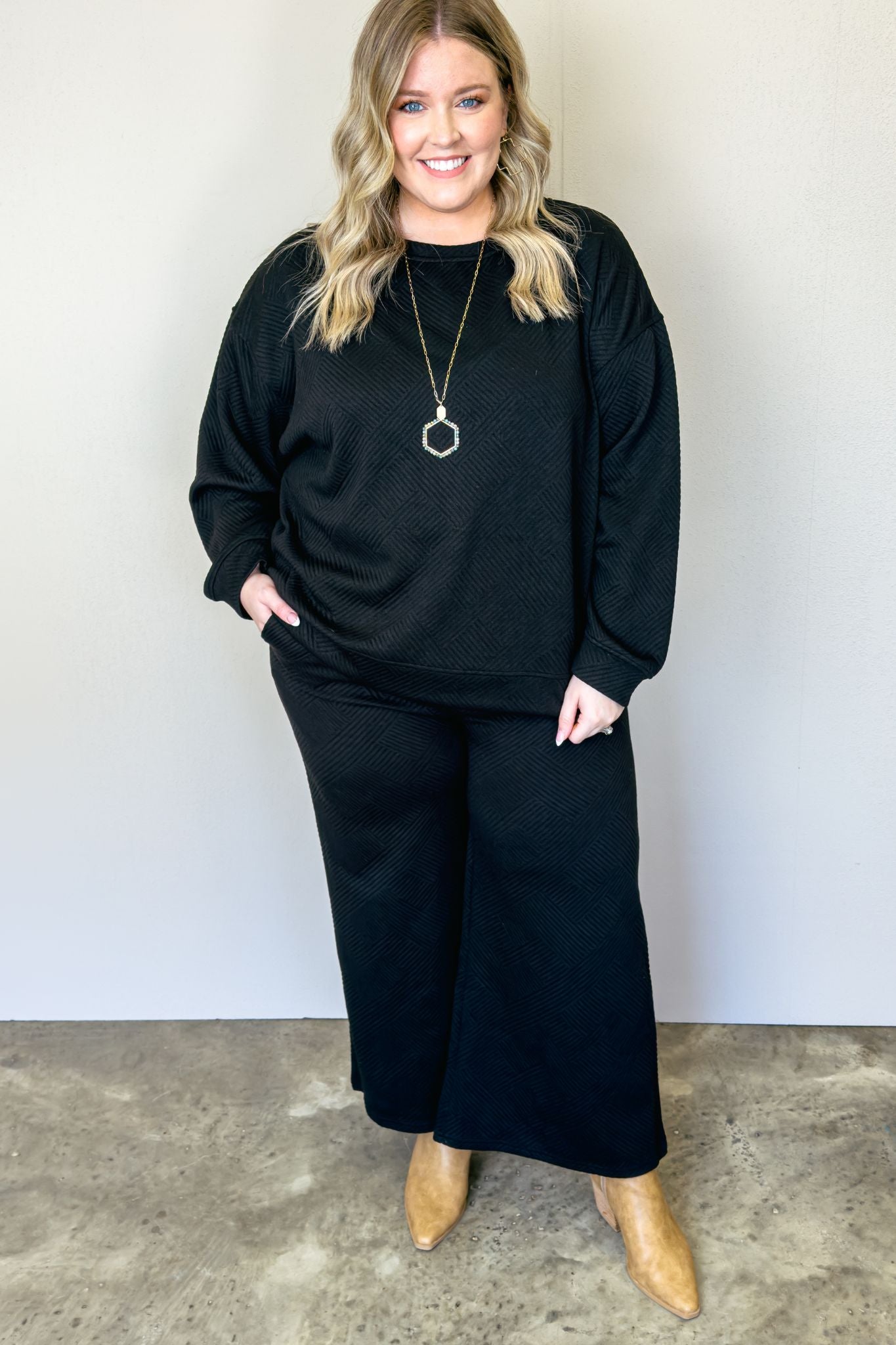 Black wide leg pants made from soft, stretchy fabric. Versatile set with textured top and crop pant. Perfect for casual or date night. Relaxed fit top, wide leg pants with pockets. Long sleeve, easy care.