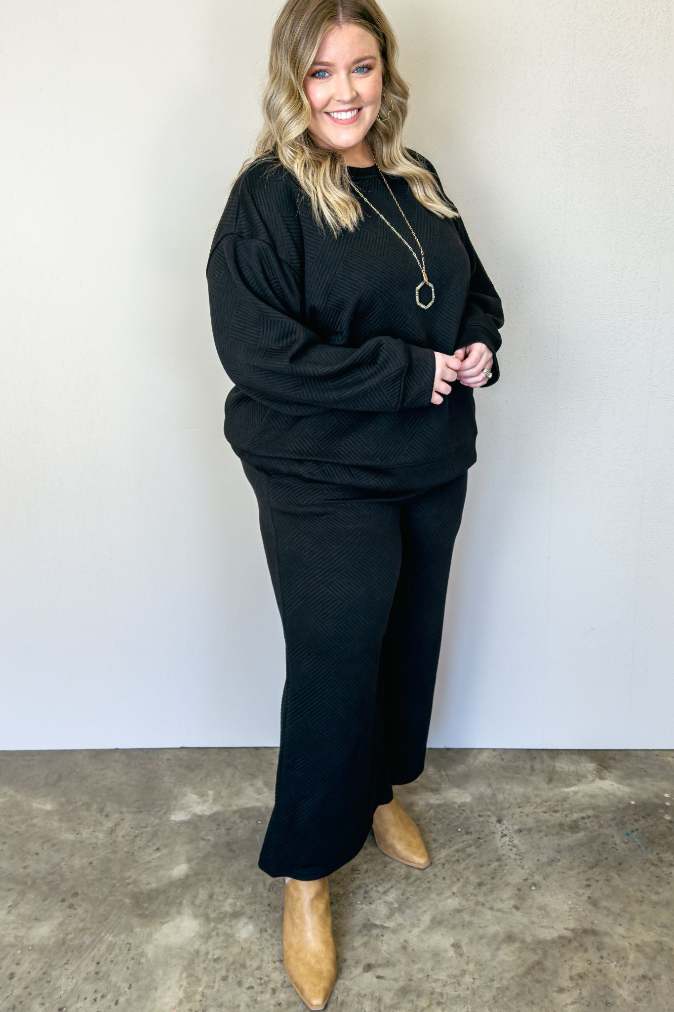 Black wide leg pants made from soft, stretchy fabric. Versatile set with textured top and crop pant. Perfect for casual or date night. Relaxed fit top, wide leg pants with pockets. Long sleeve, easy care.