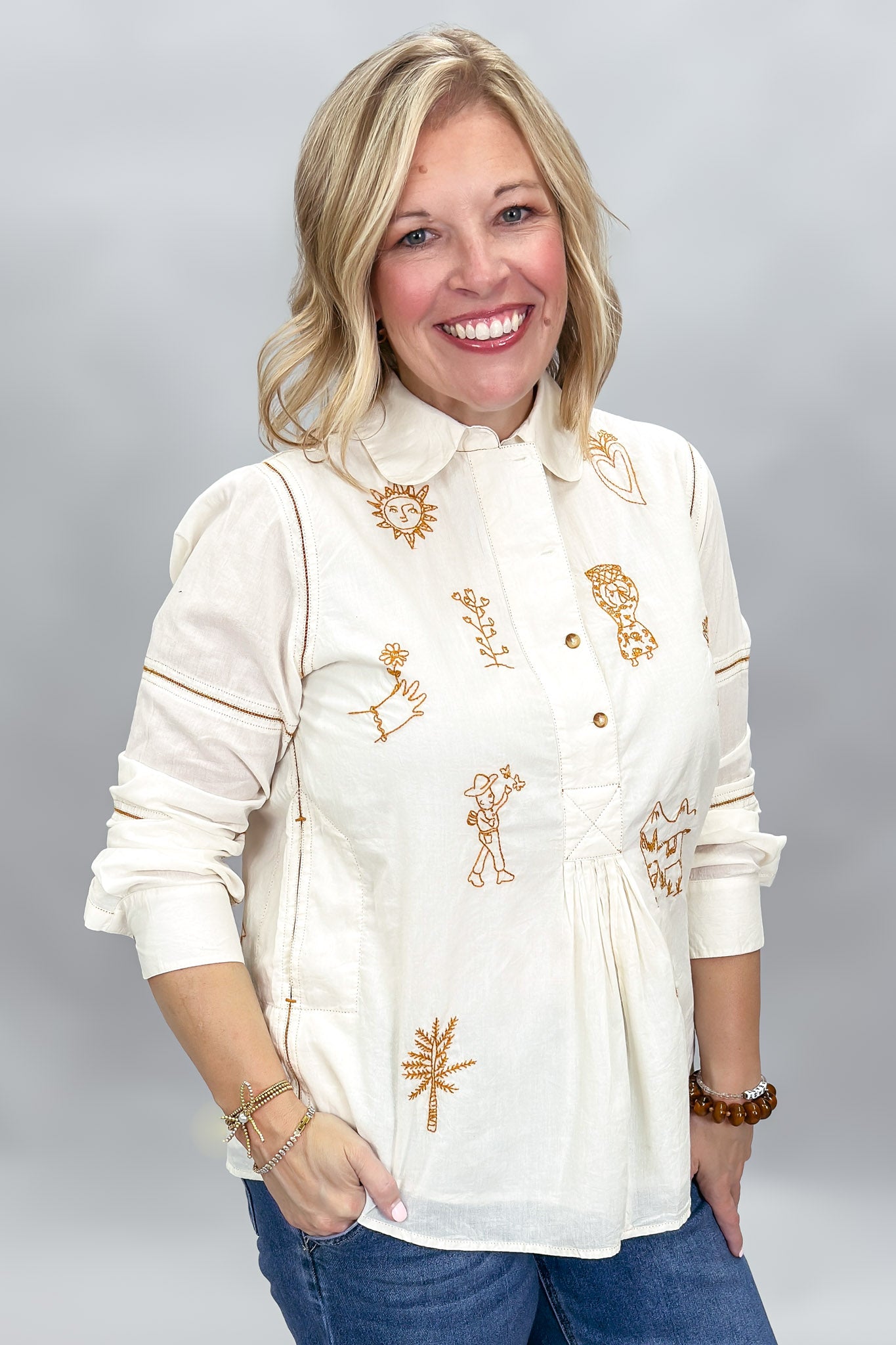 Ivy Jane ivory Milagro blouse, opposite angled view showing bronze motifs and curved hem.