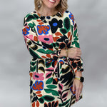 Model wearing the Back On 74 bold floral print midi dress with a cream background, colorful floral and leaf pattern, long sleeves, and a relaxed fit, front view.