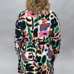 Back view of the Back On 74 bold floral print midi dress on a model, showing the belted wrap waist, long sleeves, knee-length hem, and multicolor botanical print on cream.