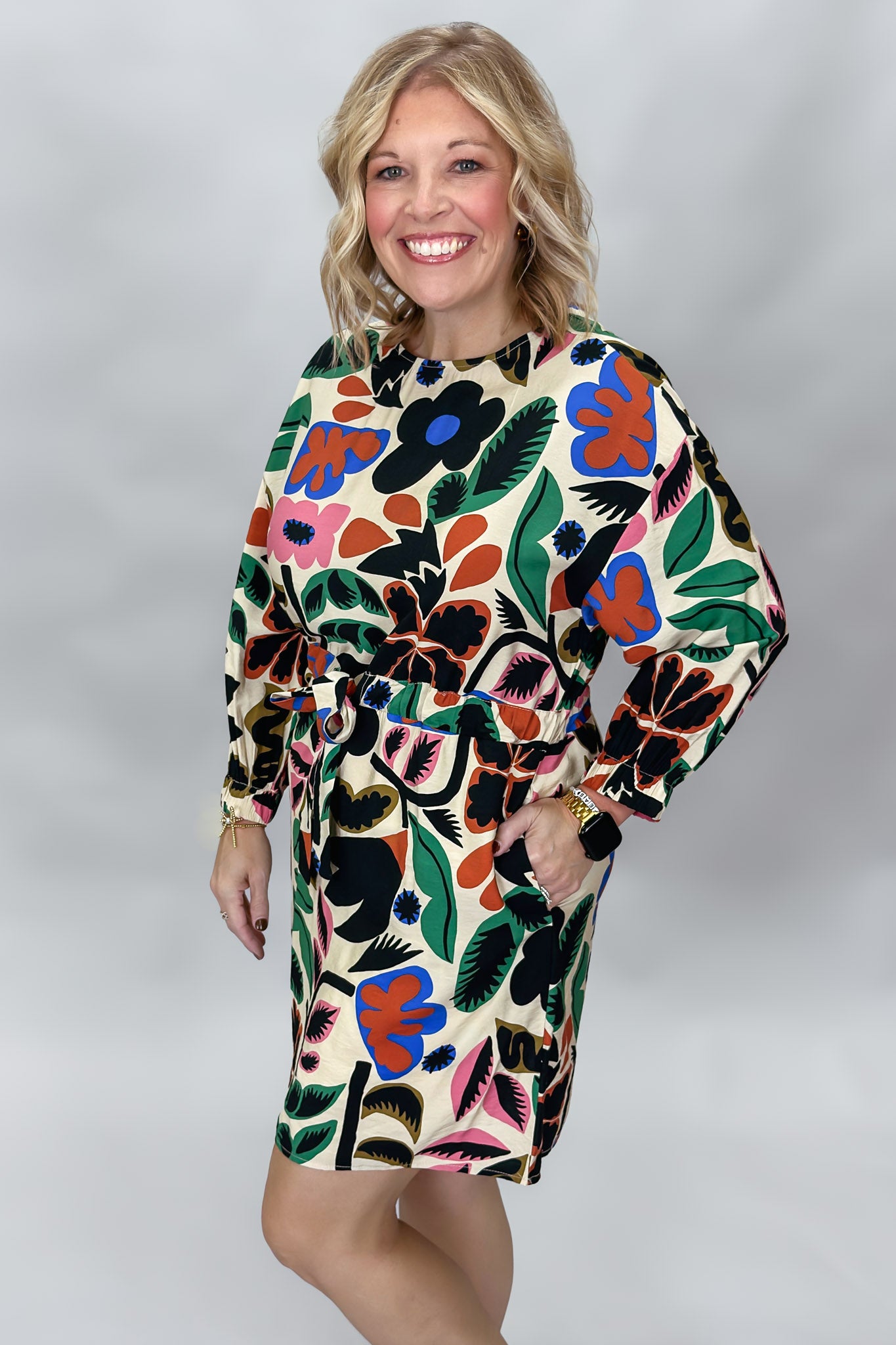 Front studio portrait of a model in the Back On 74 bold floral print midi dress, highlighting the colorful oversized flowers and leaves across the cream fabric, long sleeves, and relaxed waist.