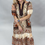 Blown My Cover cream bohemian floral midi dress with a tiered skirt, brown, beige, and orange paisley print, contrasting dark neckline, and cream Mary Jane shoes; full-length model view.