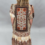Back view of the Blown My Cover bohemian midi dress, highlighting the large framed patchwork panel of rust, brown, and cream floral and geometric motifs.