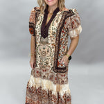 Blown My Cover cream paisley midi dress in a relaxed front pose, with short sleeves, contrasting dark neckline, tiered hem, and beige flat sandals.