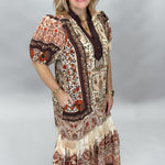 Three-quarter view of the Blown My Cover tiered floral midi dress, showing the rust, brown, and beige paisley print, short sleeves, and flowing skirt.