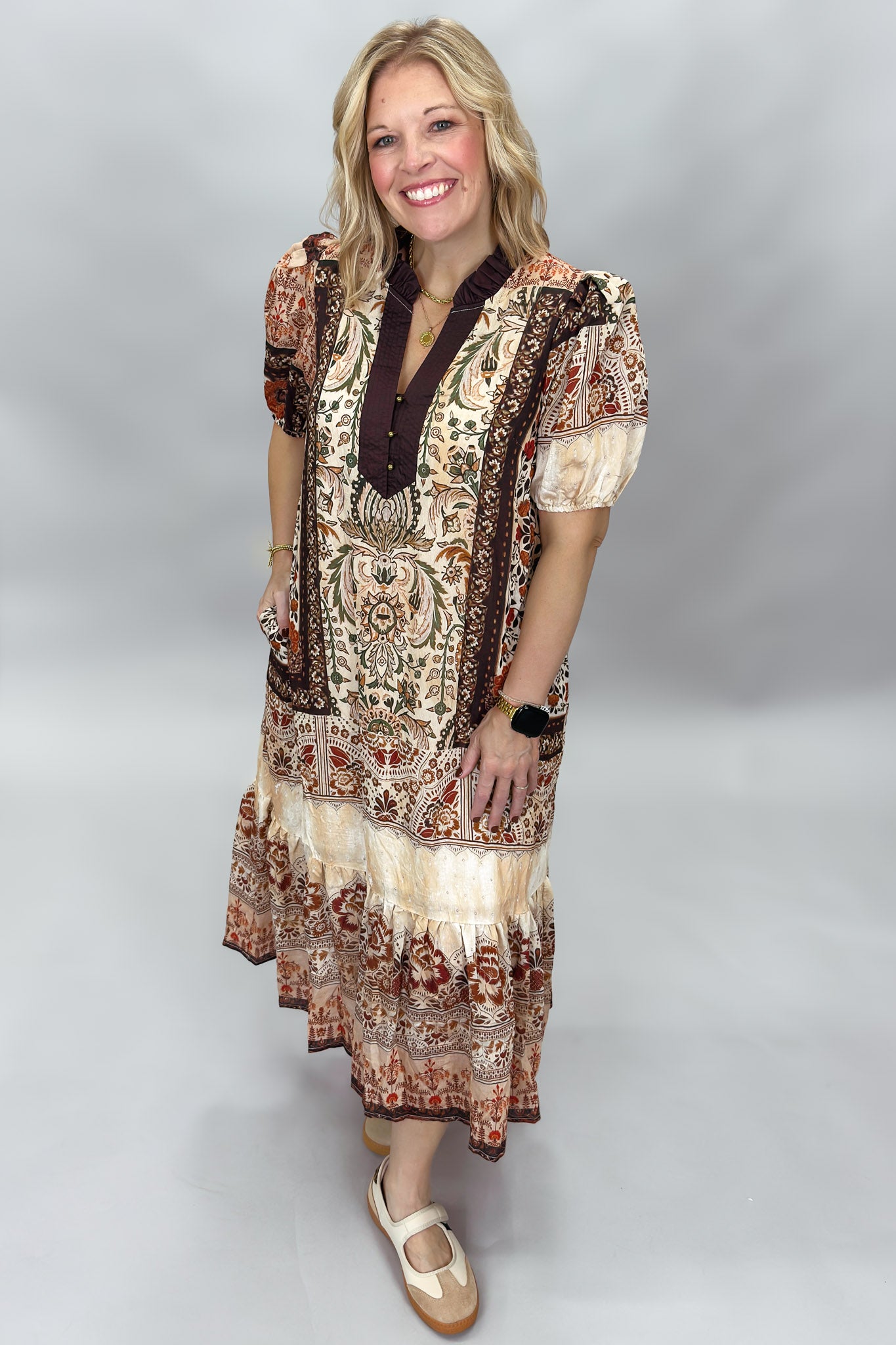 Blown My Cover cream bohemian floral midi dress in a full-length three-quarter pose, showing puff sleeves, a dark tie neckline, tiered skirt, and rust paisley print.