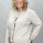 Compania Fantastica tan button-front cardigan with bow details; angled model view.