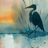 Silhouette of a heron against a colorful watercolor background with a lighthouse.