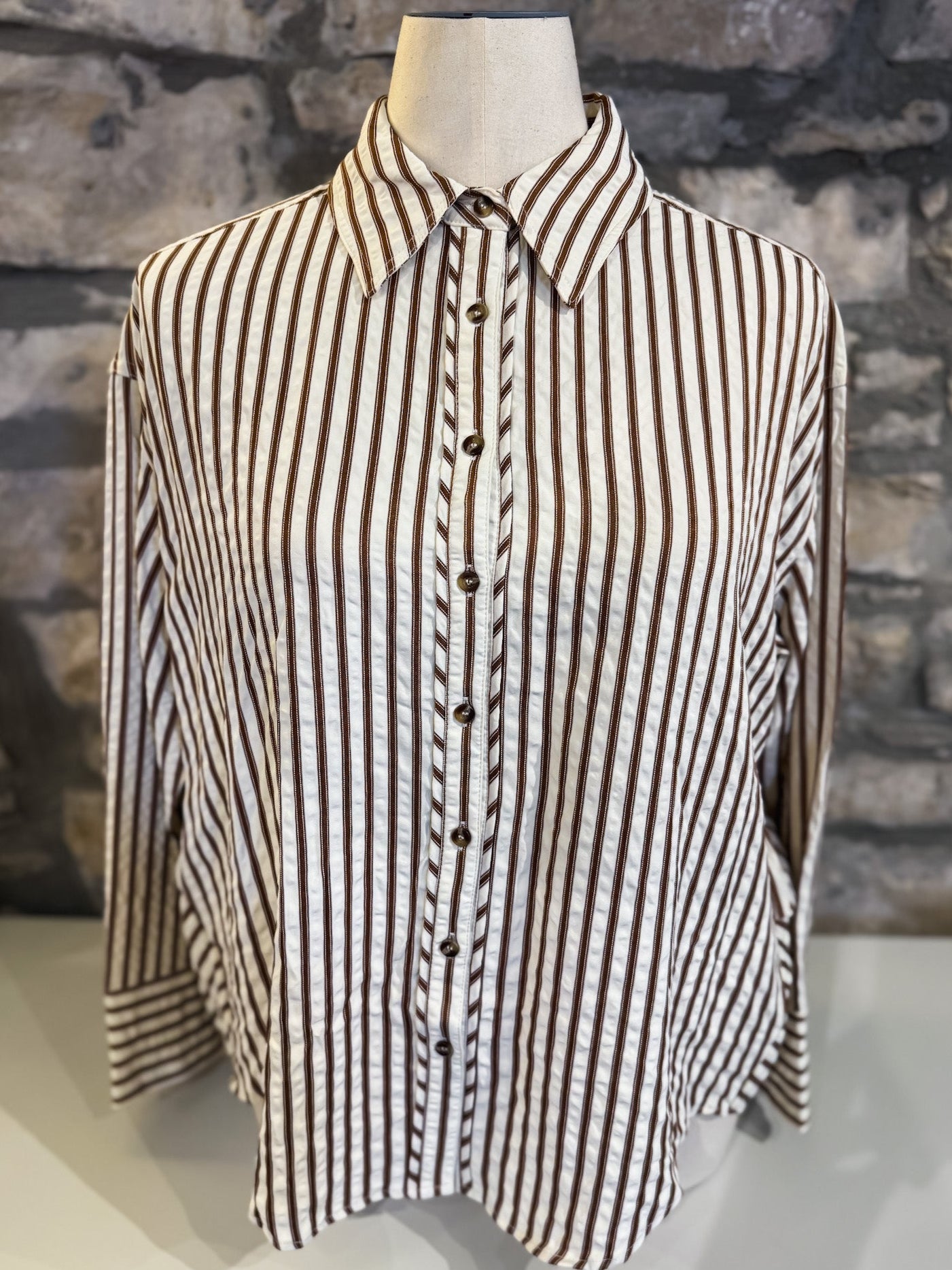 Striped shirt on a mannequin against a stone wall background