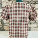 Plaid shirt on a mannequin against a stone wall background