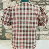 Plaid shirt on a mannequin against a stone wall background
