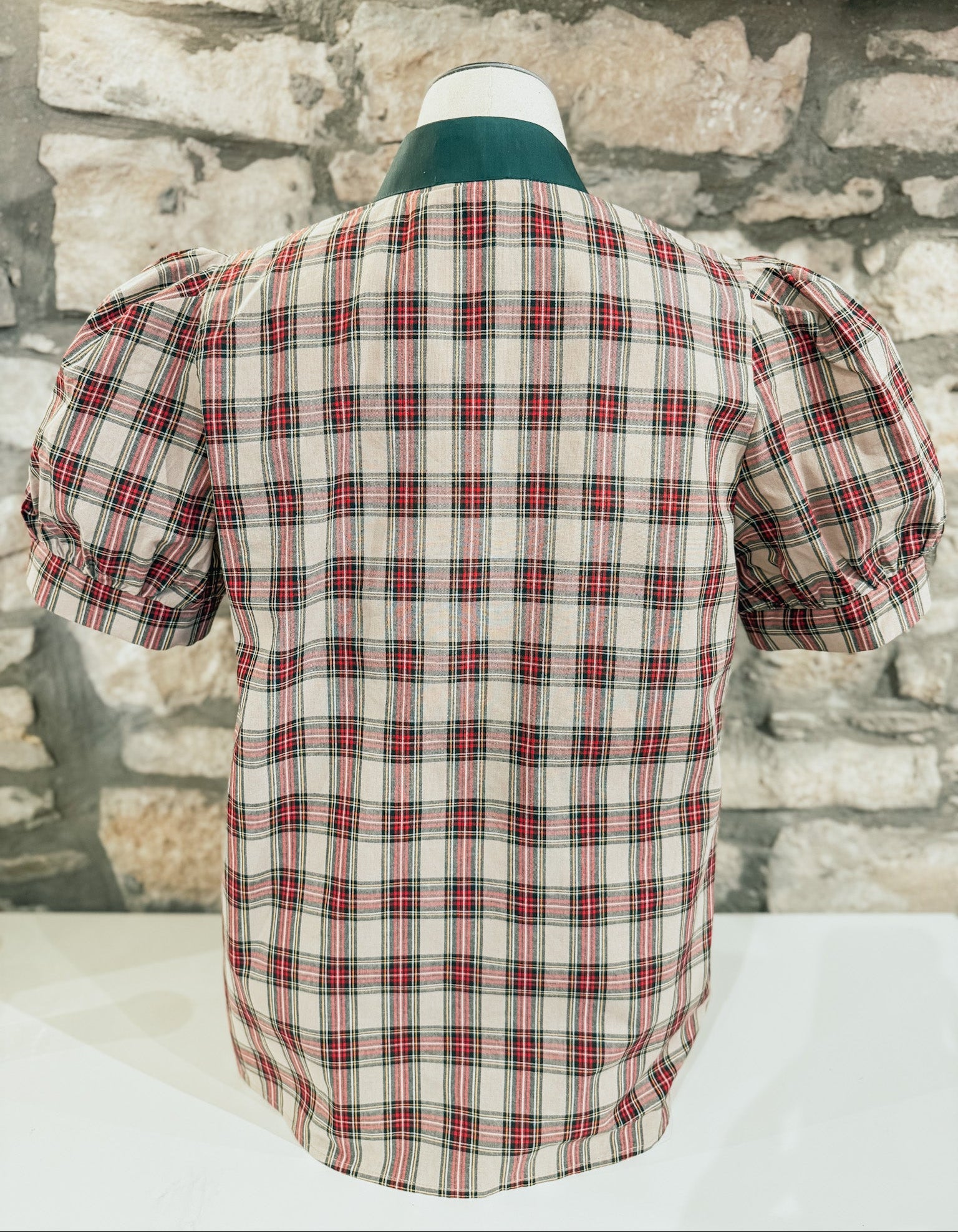 Plaid shirt on a mannequin against a stone wall background