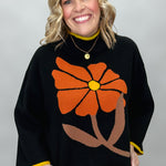 Ivy Jane black mock-neck sweater with a large orange flower; front model view.