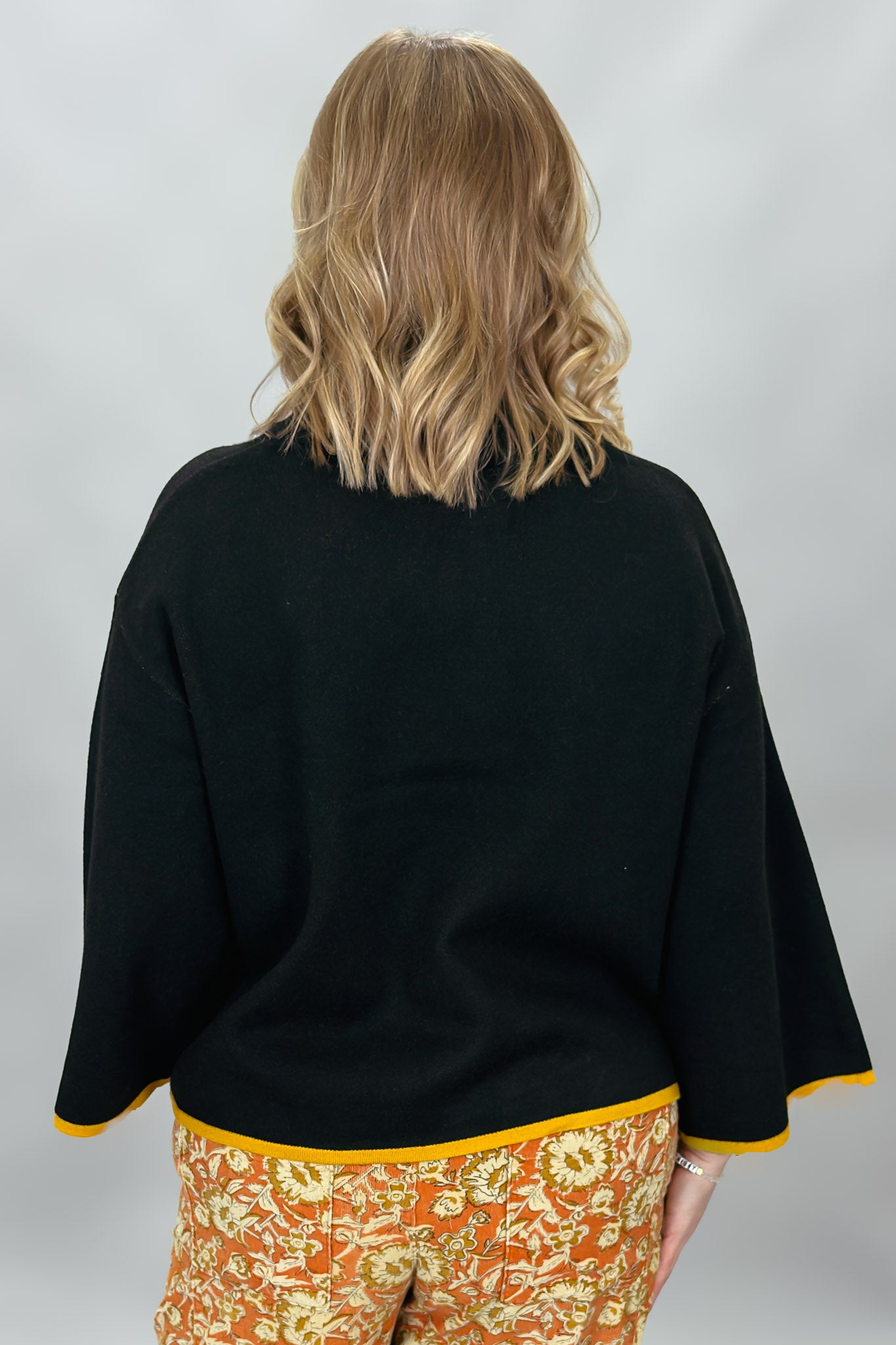 Ivy Jane black mock-neck sweater with a large orange flower; back view.