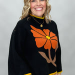 Ivy Jane black mock-neck sweater with a large orange flower; angled model view.