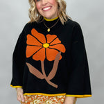 Ivy Jane black mock-neck sweater with a large orange flower; front model view.