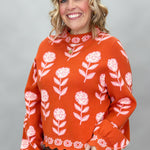 THML orange and pink floral mock-neck sweater with scalloped edges; angled model view.