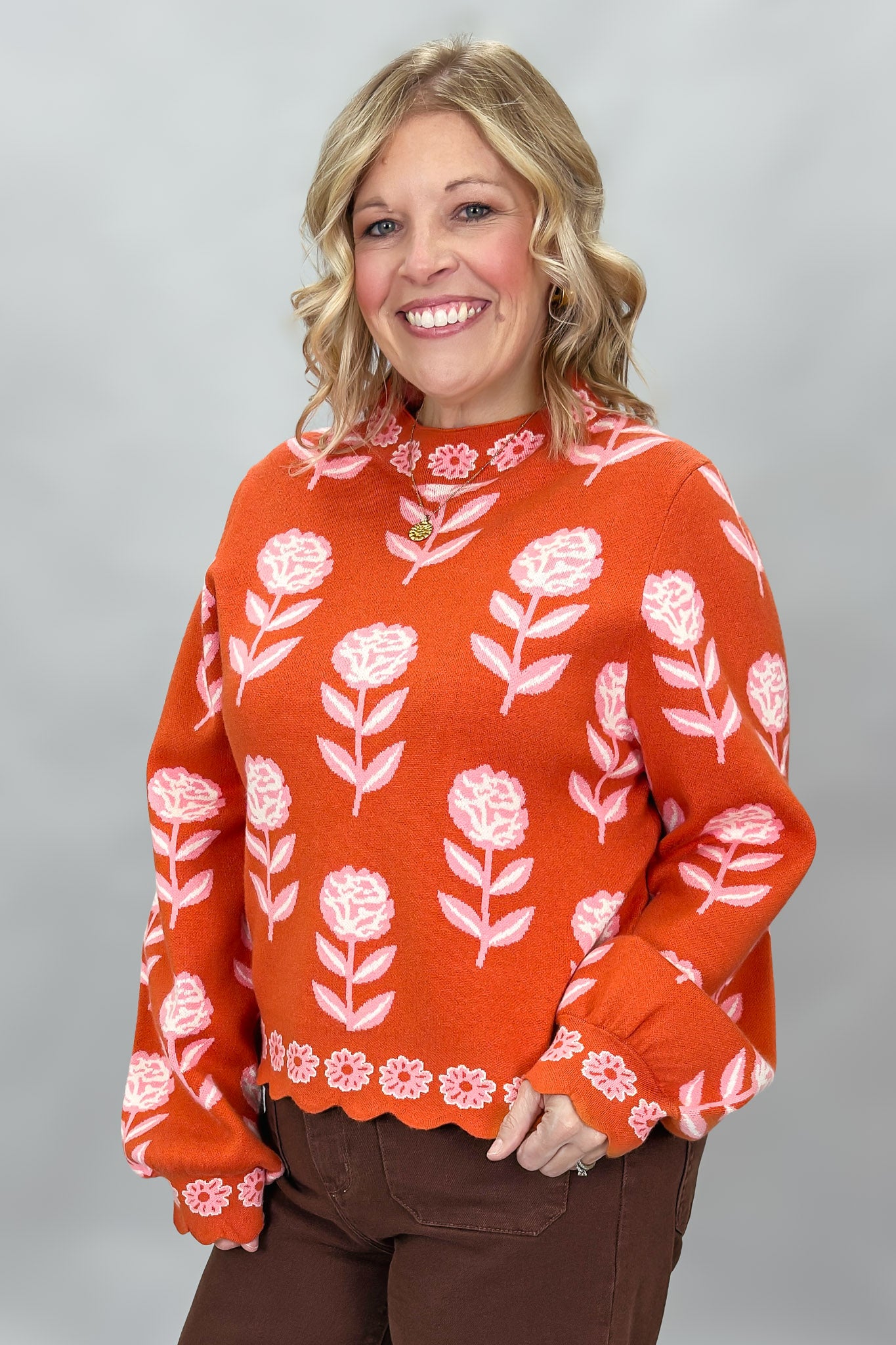 THML orange and pink floral mock-neck sweater with scalloped edges; angled model view.