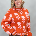 THML orange and pink floral mock-neck sweater with scalloped edges; angled model view.