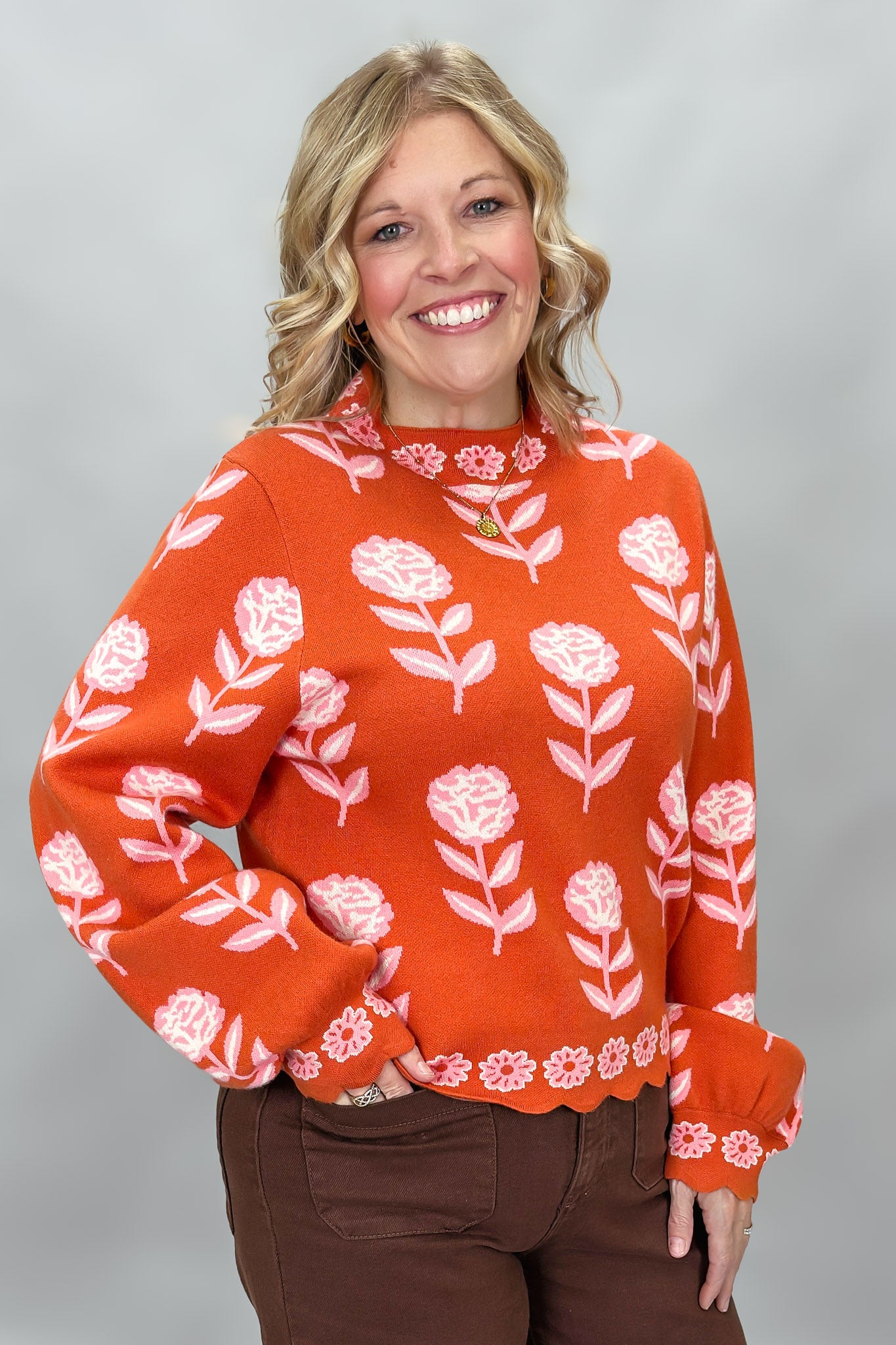 THML orange and pink floral mock-neck sweater with scalloped edges; angled model view.
