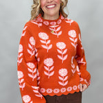 THML orange and pink floral mock-neck sweater with scalloped edges; front model view.
