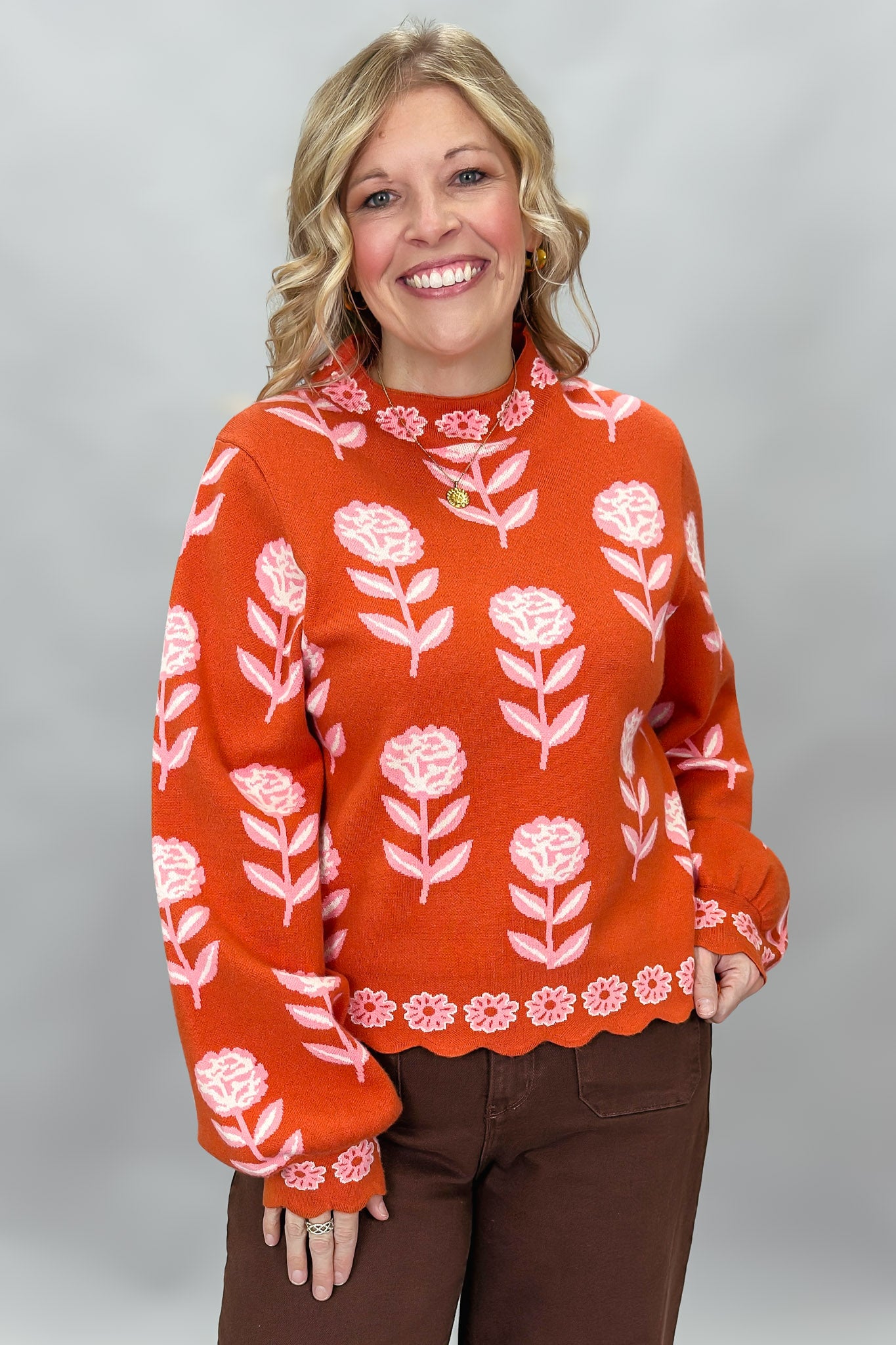 THML orange and pink floral mock-neck sweater with scalloped edges; front model view.