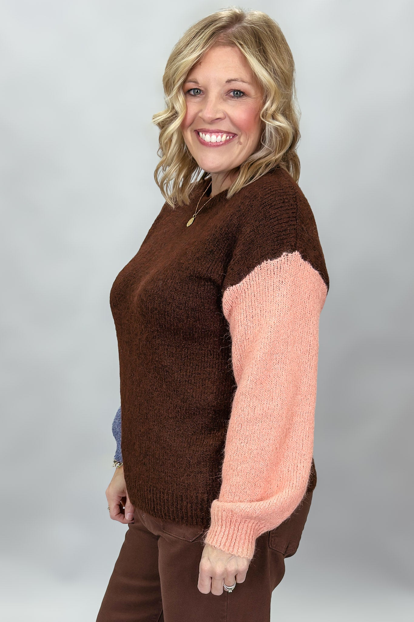 Compania Fantastica mocha sweater with blue and pink sleeves; angled model view.