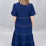Mary Square navy tiered dress with contrast piping and short puffed sleeves; back view.