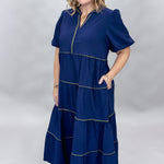 Mary Square navy tiered dress with contrast piping and short puffed sleeves; angled model view.
