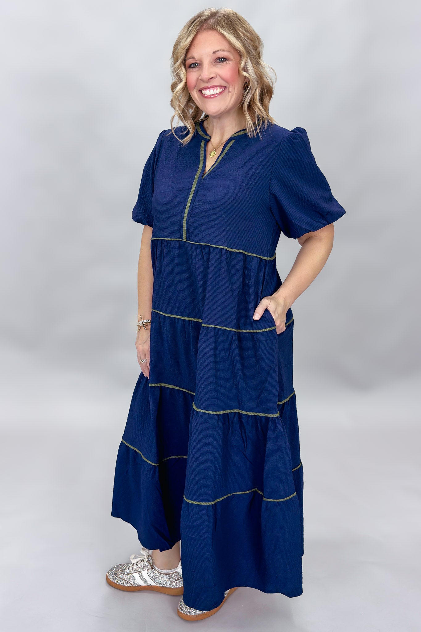 Mary Square navy tiered dress with contrast piping and short puffed sleeves; angled model view.