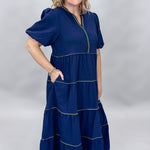 Mary Square navy tiered dress with contrast piping and short puffed sleeves; angled model view.