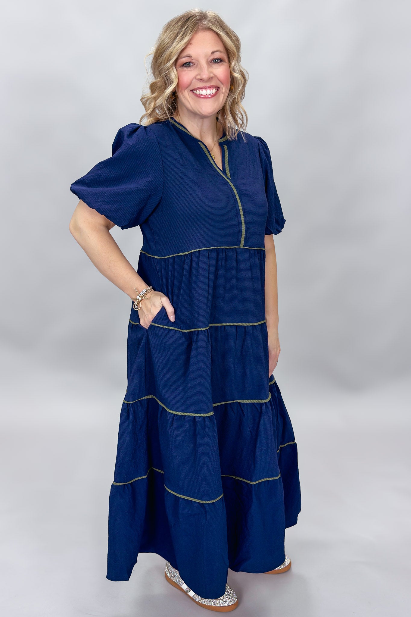 Mary Square navy tiered dress with contrast piping and short puffed sleeves; angled model view.