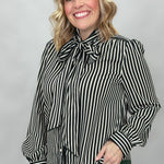 FATE black and cream striped tie-neck blouse with gathered cuffs; angled model view.