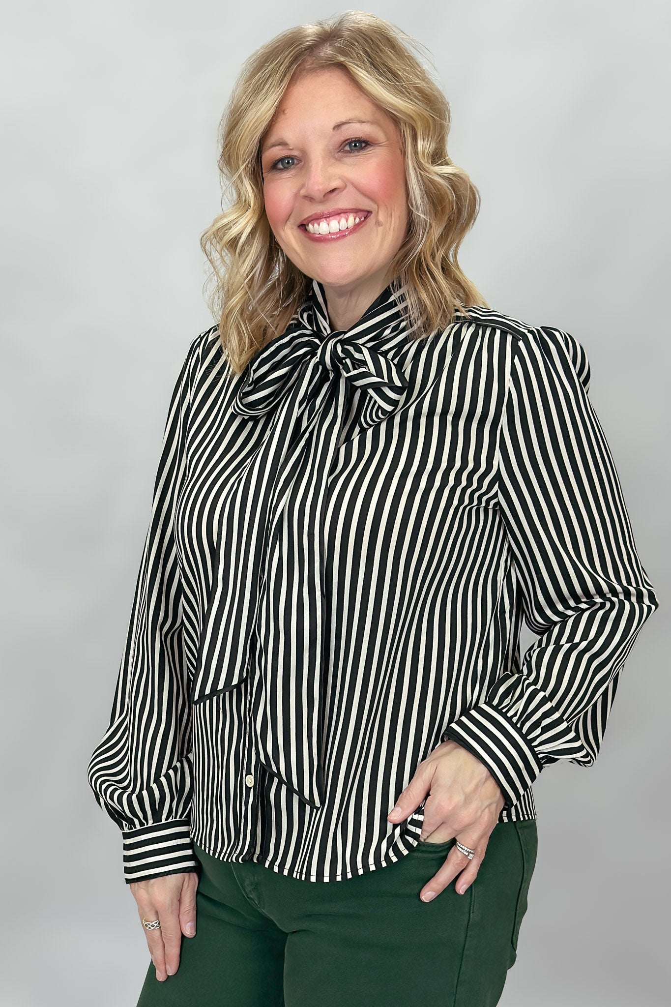 FATE black and cream striped tie-neck blouse with gathered cuffs; angled model view.