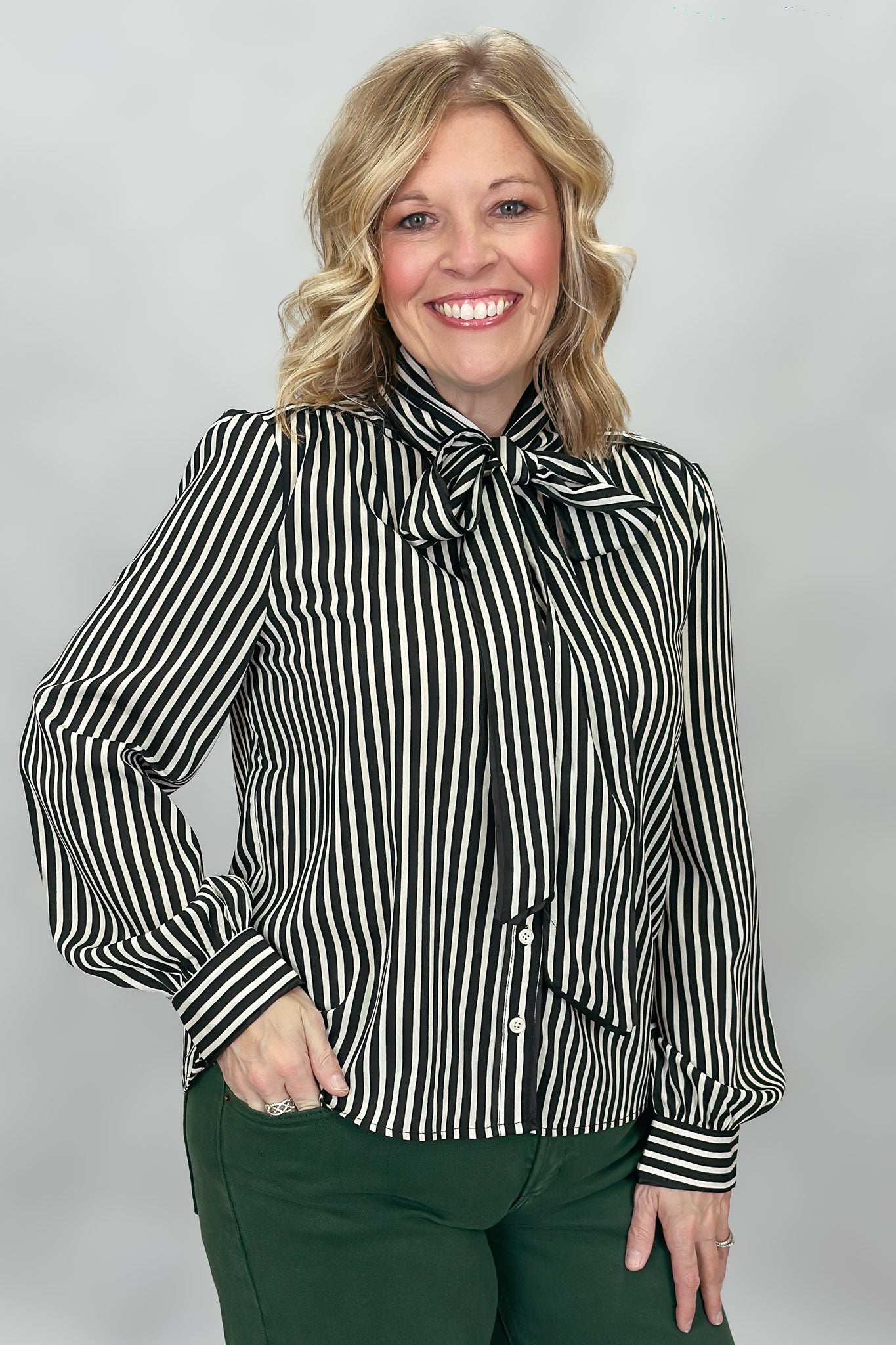 FATE black and cream striped tie-neck blouse with gathered cuffs; angled model view.